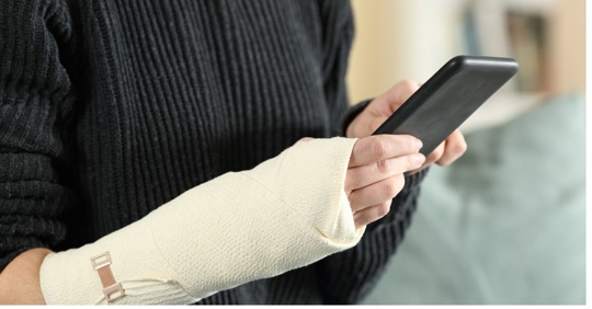 woman holding a cell phone with her arm in a cast.
