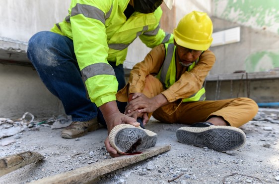 supervisor examining construction worker with an injured foot